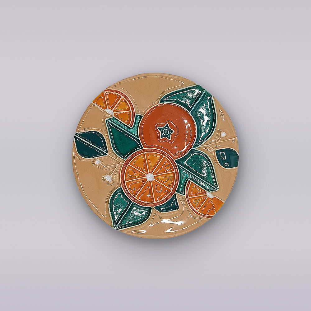 A round Algarve ceramic plate with a vibrant orange, leaf, and flower design on beige—perfect for pairing with the Miradouro Ceramics Algarve Sandstone Orange Ceramic Coaster.