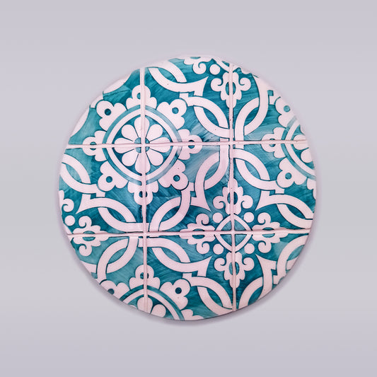A circular arrangement of blue and white decorative tiles featuring intricate patterns of interwoven, stylized floral and geometric designs. This hand-painted **Carcavelos Ceramic Table Trivet** from **Tejo Shop** forms a symmetrical motif across the entire circle, creating a visually appealing and harmonious artisanal kitchen accessory.