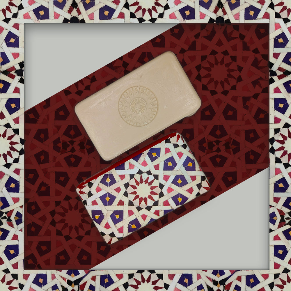 Ceuta 1415 – The First Horizon soap by 100ml, one beige with a circular pattern and another wrapped in multicolored geometric paper, are displayed on a red and white Islamic-style mosaic background.