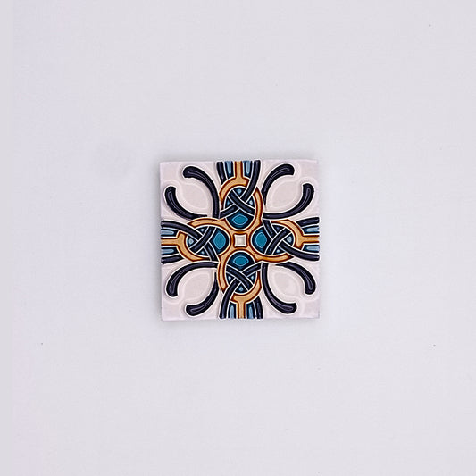 A Tejo Shop hand-painted ceramic tile with a symmetrical geometric pattern, featuring intricate blue, black, and orange designs on a white background. The pattern includes both curved and angular elements, ideal to elevate your