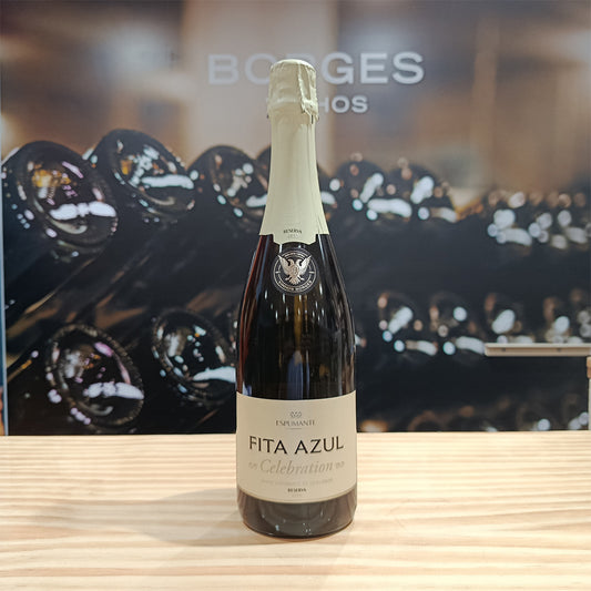 A bottle of Fita Azul Celebration Reserve Dry by Borges Wines stands on a wooden surface, with blurred wine bottles and the brand name "Borges" visible in the background.