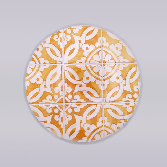 A Guimaraes Ceramic Trivet for Hot Pans from Tejo Shop with an intricate, symmetrical white geometric pattern resembles traditional tile designs. Hand-made with a warm, natural wood background, it brings a touch of artisanal charm to any kitchen. The trivet is set against a plain, grayish backdrop.