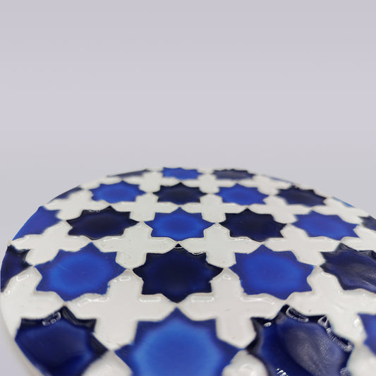 Close-up of the Heritage Blue Star Mosaic Coaster by Miradouro Ceramics, featuring blue star and white cross shapes in a geometric azulejo-inspired pattern, set against a plain light gray background.