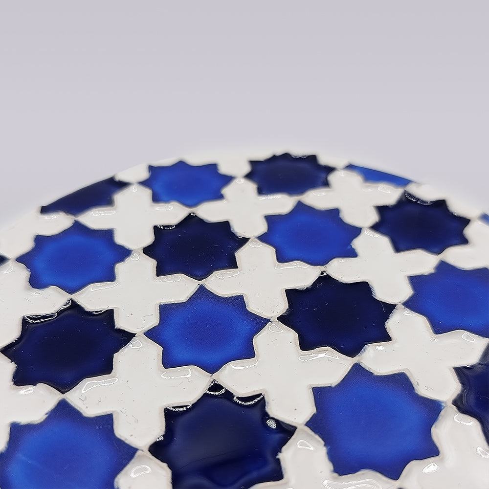 A close-up of the Heritage Blue Star Mosaic Coaster by Miradouro Ceramics, showing its glossy ceramic surface with a geometric pattern of white and blue star shapes inspired by traditional azulejo mosaics.