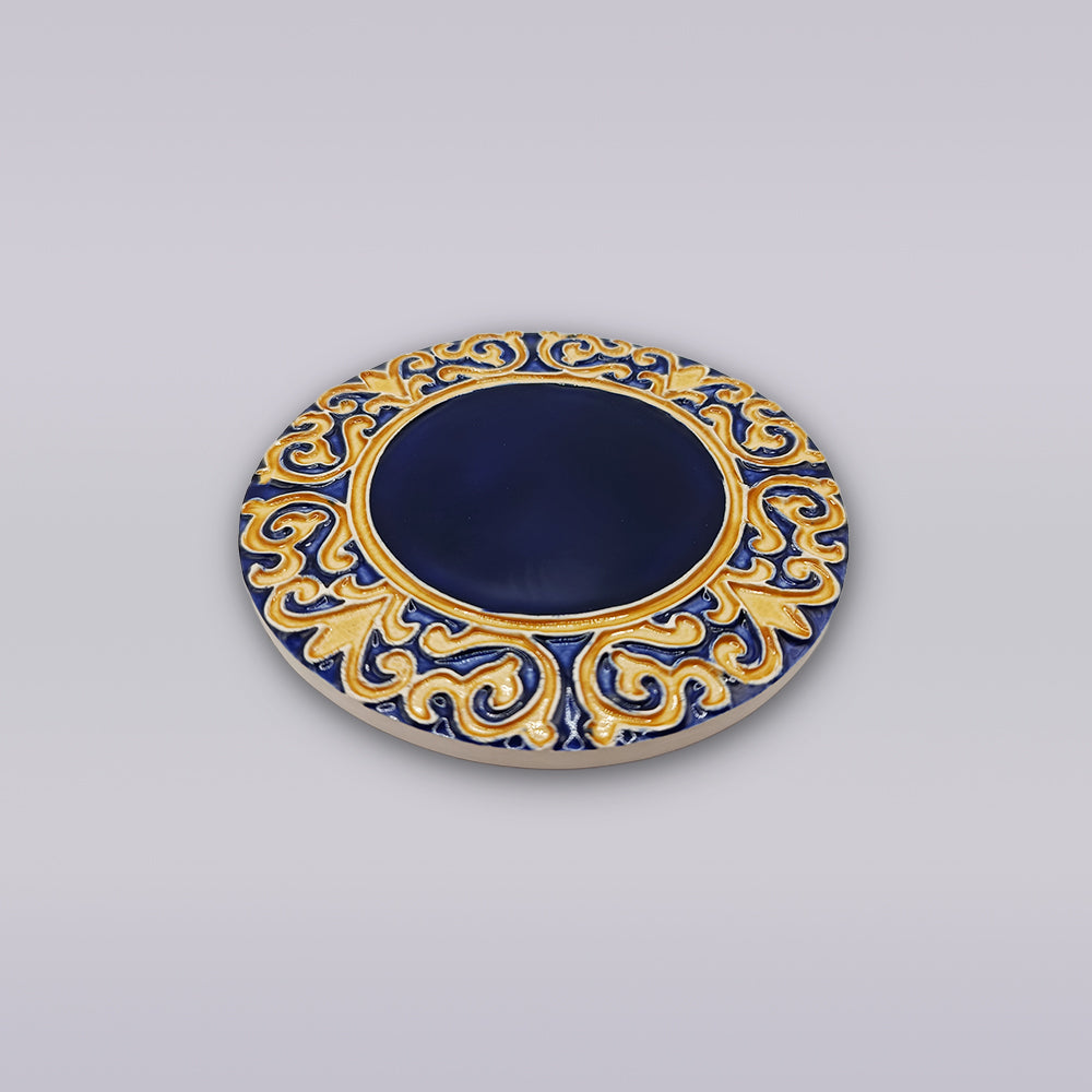 The Manuel I Royal Crest Ceramic Coaster by Miradouro Ceramics features a deep blue center with an ornate gold and blue border, evoking Portuguese style, displayed on a light gray background.