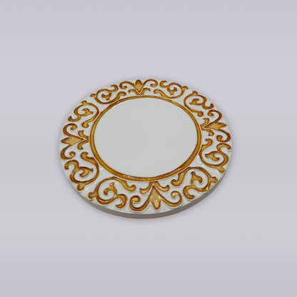The Manueline Golden Crest Ceramic Coaster by Miradouro Ceramics features an intricate gold pattern of swirls and hearts on a round, white surface, inspired by classic Portuguese decor, set against a plain white background.