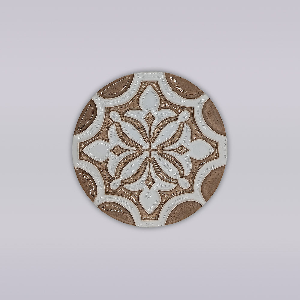 The Ocre Fleur coaster by Miradouro Ceramics is a round, hand-painted ceramic piece with a brown and white geometric floral design on light gray—an artisanal touch for your home décor.