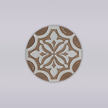 The Ocre Fleur coaster by Miradouro Ceramics is a round, hand-painted ceramic piece with a brown and white geometric floral design on light gray—an artisanal touch for your home décor.