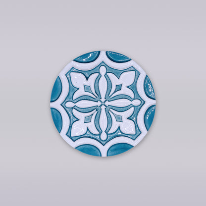 The Rosacrux Atlântica by Miradouro Ceramics is a round ceramic tile with a blue and white geometric design on light gray, ideal as a stylish decorative coaster for any setting.