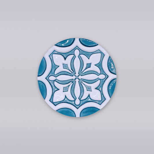 The Rosacrux Atlântica by Miradouro Ceramics is a round ceramic tile with a blue and white geometric design on light gray, ideal as a stylish decorative coaster for any setting.