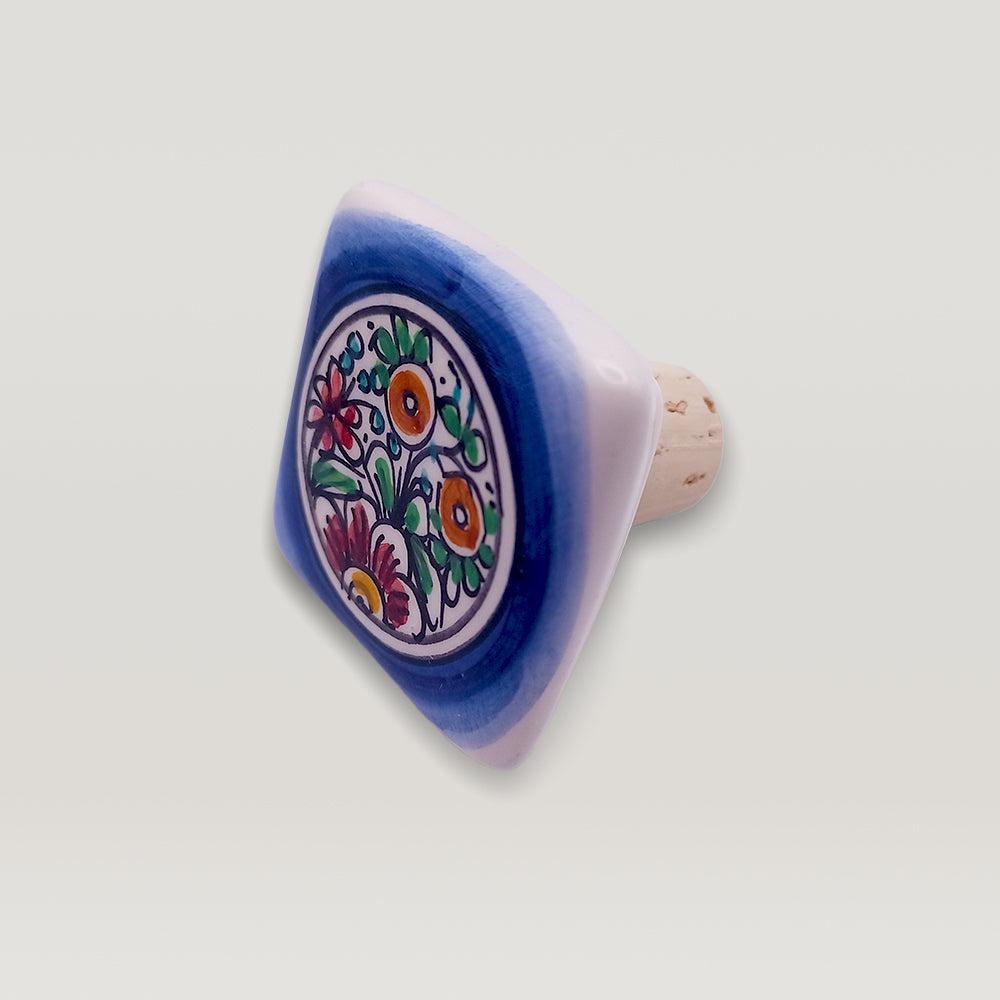 A Tejo Shop hand-painted ceramic wine bottle stopper with floral design on a white background.