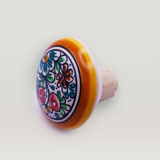 Colorful handcrafted Tejo Shop ceramic wine bottle stopper with floral pattern on a white background.