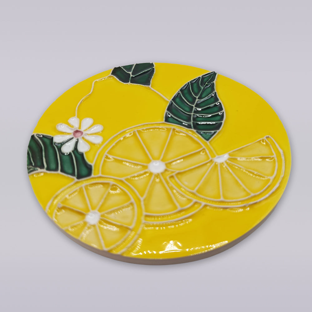The Tejo Lemon Blossom Coaster – Ribatejo Edition by Miradouro Ceramics features embossed lemon slices, green leaves, and a white flower with a pink center, inspired by traditional Ribatejo artisan decor.