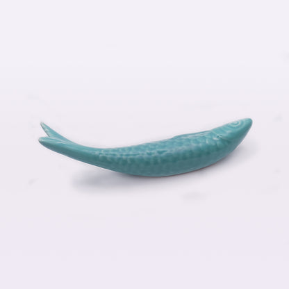 A small, turquoise ceramic sculpture of a fish with detailed scales, a textured body, and a slightly curved shape. This piece showcases traditional craftsmanship typical of handcrafted Portuguese ceramics and is placed on a plain white background. The product is called Portuguese Ceramic Sardines by Tejo Shop.