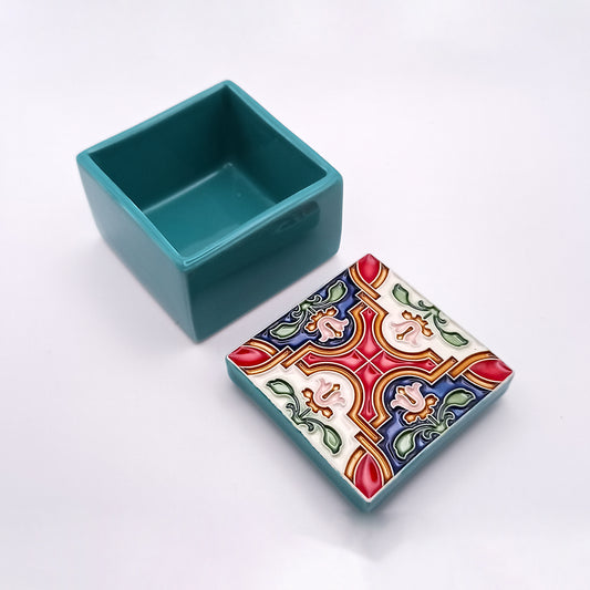 The sophisticated Aveiro Ceramic Box by Tejo Shop, with its lid removed, showcases a colorful, ornate design featuring red, blue, green, and white patterns in symmetrical shapes reminiscent of traditional tile work. Handcrafted with care, the inside of the box retains a plain turquoise finish.