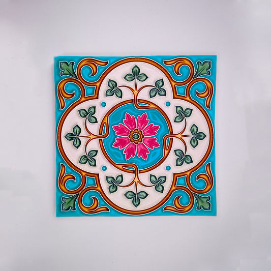 A colorful hand-crafted ceramic tile with a decorative pattern featuring a pink floral design at the center surrounded by green leaves and blue and orange swirls on a white background from Tejo Shop's Hand Made Painted Tile.