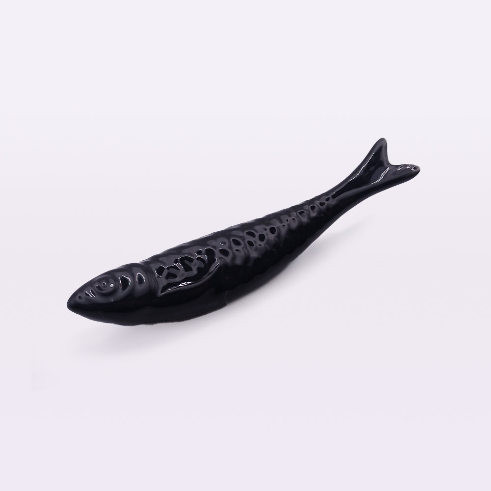 A Portuguese Ceramic Sardine from Tejo Shop, crafted with traditional craftsmanship. The sardine has a smooth, glossy finish with hollowed-out patterns on its body, resembling scales, and a curved tail. Perfect for home decor, the sardine is displayed on a plain, light background reminiscent of Portuguese ceramic sardines.