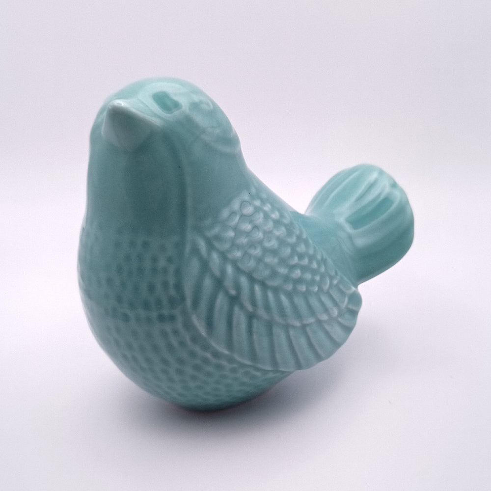 Introducing the Ceramic Bird looking up Figurine by Tejo Shop. This small, turquoise ceramic bird features intricate details on its wings and body, making it perfect for home decor. The figurine has a round shape, a raised beak, and an elegant tail, all showcased in a smooth and glossy finish. Placed against a plain white background, the handmade craftsmanship of this beautiful piece truly stands out.