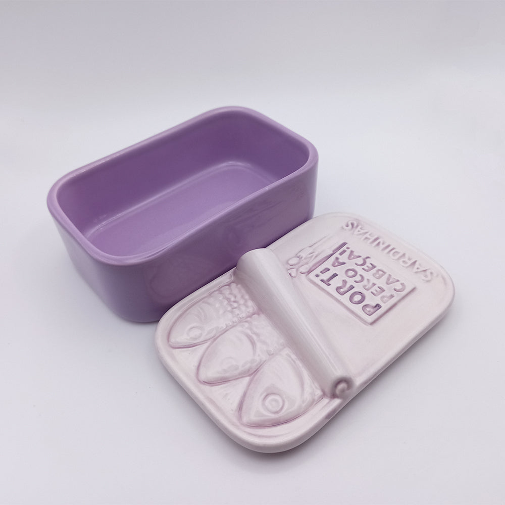 A purple ceramic dish from the "I'm Crazy About You" collection by 100ml, featuring a partially open lid designed like a sardine tin. The lid has raised fish details and reads "Porta Bescca Capsule," perfect as a hand-painted ceramic soap box against its plain white background.