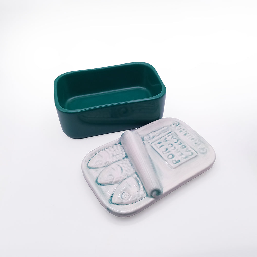 The "Hand-painted Ceramic Soap Box - Aguada Edition" by 100ml is a rectangular, dark green container featuring an open lid with a metallic finish. The design mimics a sardine can with three fish and the phrase "PORK WITH AUCUN LIMITES.