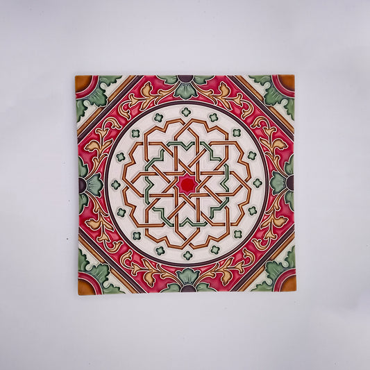 A Tejo Shop decorative high-quality ceramic tile featuring a complex geometric pattern with interlocking shapes in shades of red, green, white, and orange, centered within a square format on a plain background.
