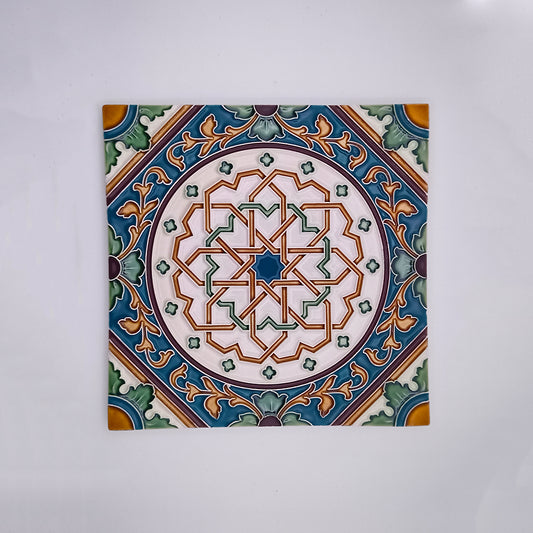 A Tejo Shop square hand-painted ceramic tile featuring a detailed geometric and floral pattern in vibrant colors of green, blue, orange, and white, with a symmetrical design centered on the tile.
