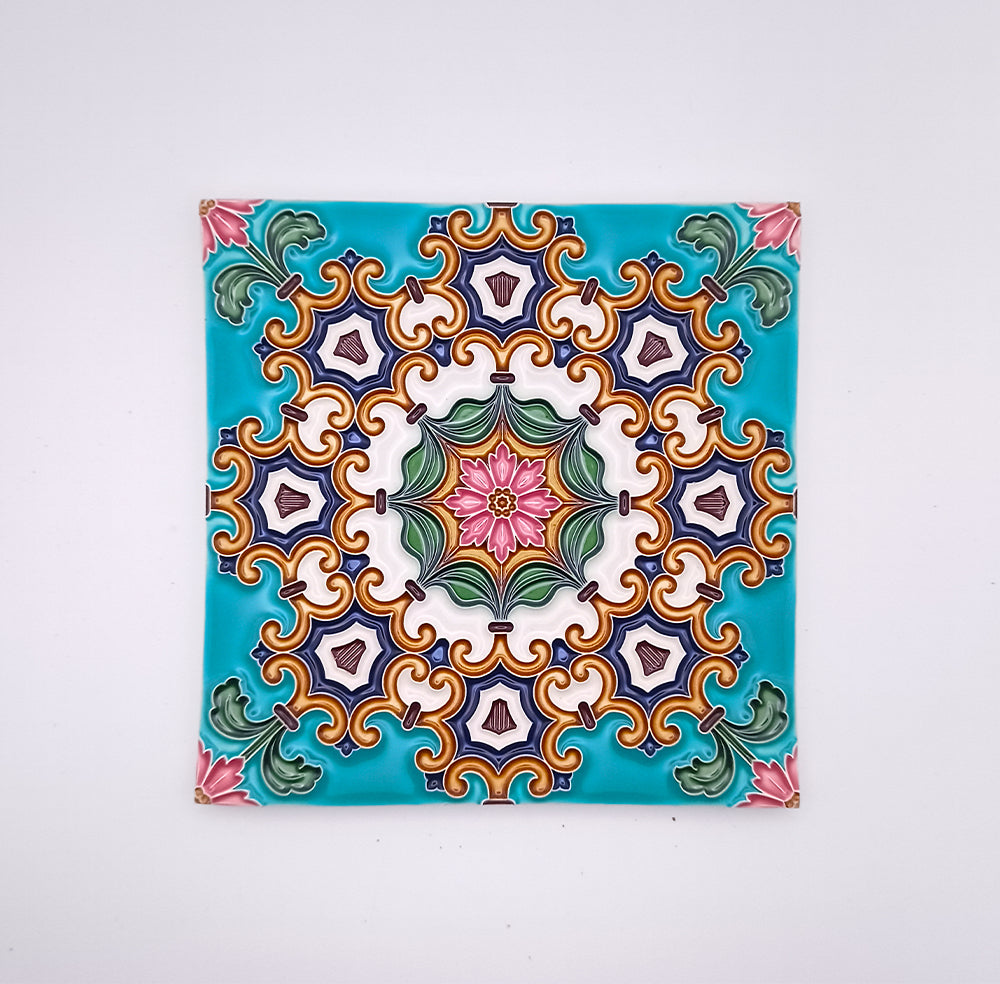 Decorative ceiling tile featuring a symmetrical, colorful pattern with floral motifs in shades of green, pink, purple, and yellow, centered on a hand-crafted turquoise background by Tejo Shop.