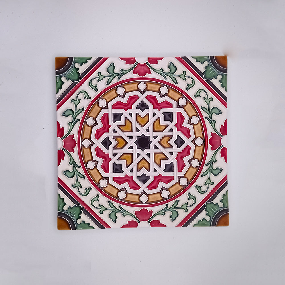 A Tejo Shop hand-painted decorative ceramic tile featuring a symmetrical, intricate geometric and floral pattern in red, green, white, and beige colors on a neutral background.