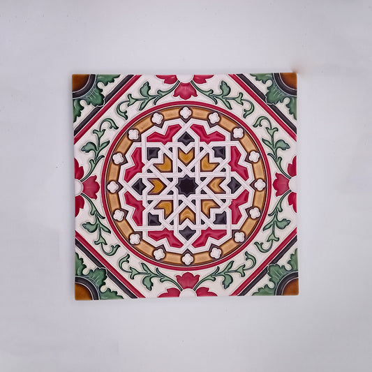A Tejo Shop hand-painted decorative ceramic tile featuring a symmetrical, intricate geometric and floral pattern in red, green, white, and beige colors on a neutral background.