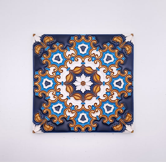 Decorative Drop Ceiling Tiles by Tejo Shop, hand painted with a symmetrical pattern featuring blue, gold, and white colors, hung on a white wall with visible nails at each corner.