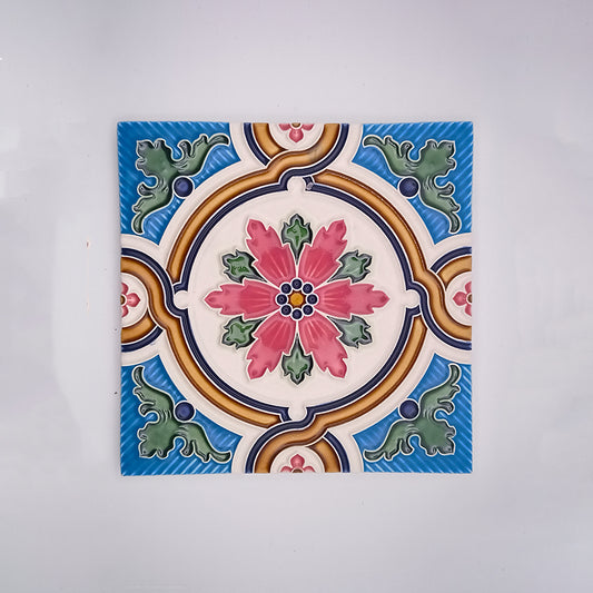 A hand-painted Decorative Fireplace Tile featuring a symmetrical, colorful floral design with pink, blue, green, and yellow elements on a white background by Tejo Shop.
