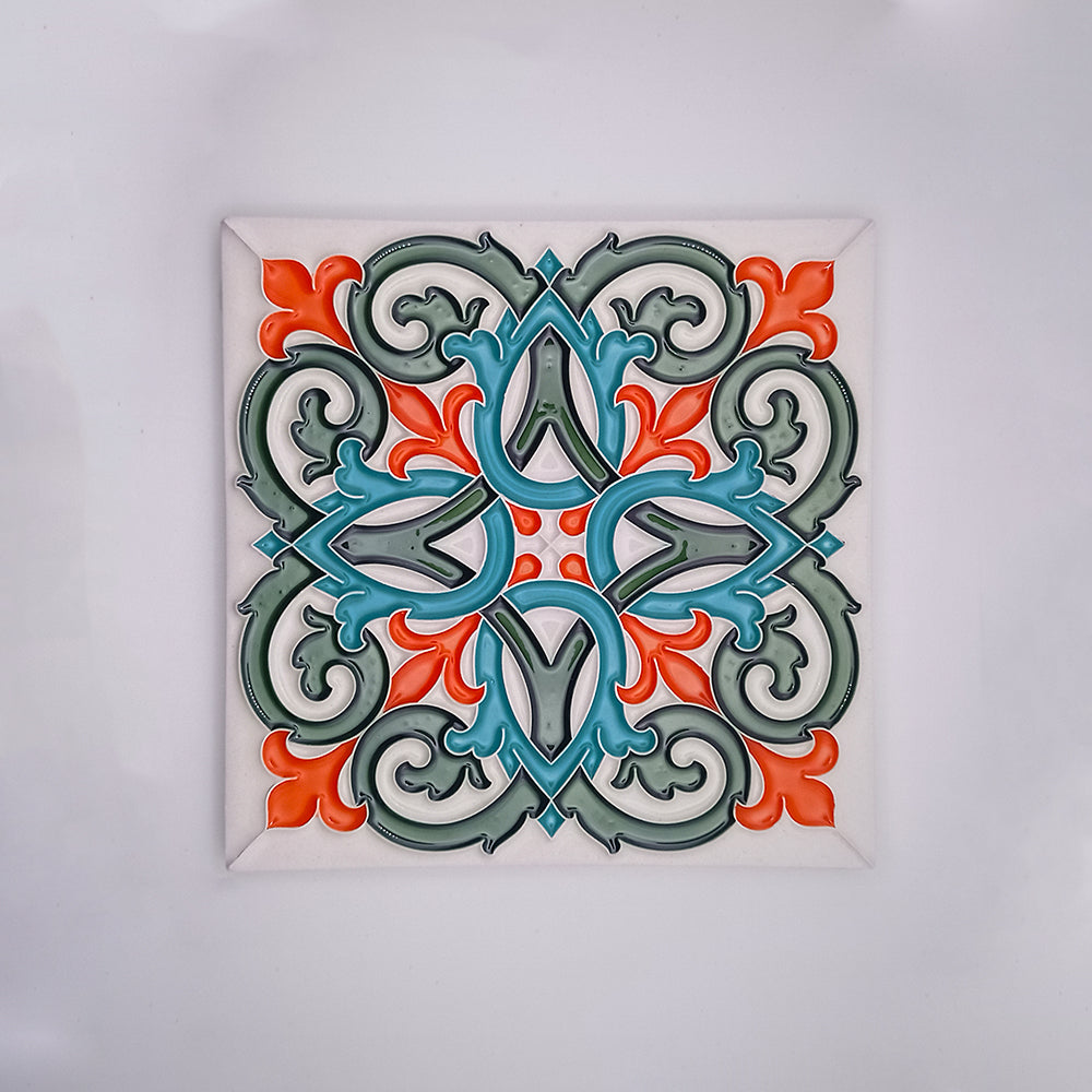 A colorful Tejo Shop Intrinsic Decorative Tile featuring a symmetrical, ornate pattern in shades of teal, grey, and orange, encased within a square white frame against a light background.