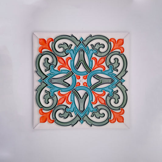 A colorful Tejo Shop Intrinsic Decorative Tile featuring a symmetrical, ornate pattern in shades of teal, grey, and orange, encased within a square white frame against a light background.