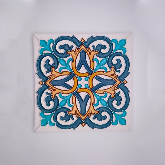 Handmade decorative ceramic tile with a symmetrical, intricate design featuring interlocking curves and floral motifs in shades of blue, gold, and brown, framed in white by Tejo Shop's hand-painted Tiles for Walls.
