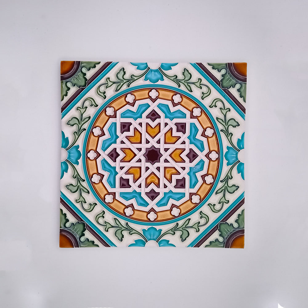 Tejo Shop's handmade decorative tiles feature a detailed, symmetrical geometric pattern in shades of blue, green, orange, and white, set against a neutral background.