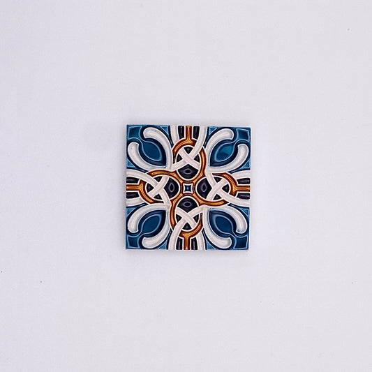 A decorative Hand Painted Portuguese Ceramic Tile from Tejo Shop featuring a symmetrical, geometric pattern with interlocking designs predominantly in blue, white, and dark red colors on a neutral background.