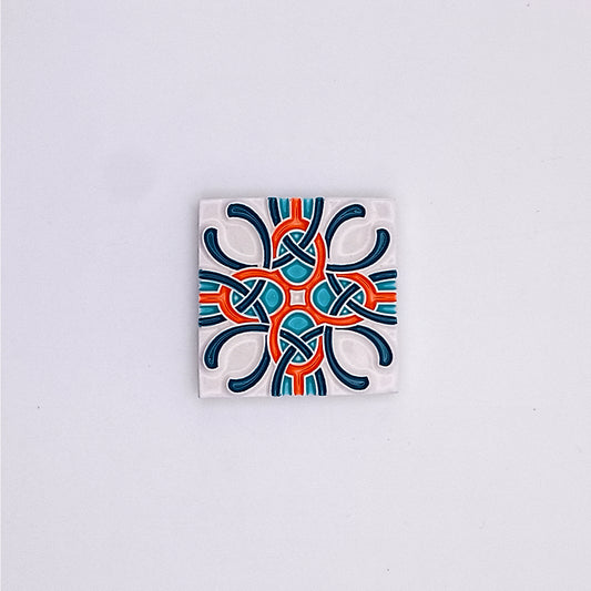 A square hand-painted ceramic tile featuring a symmetrical, intricate design in blue, orange, and white colors against a pale gray background by Tejo Shop's Portuguese Small Tiles.