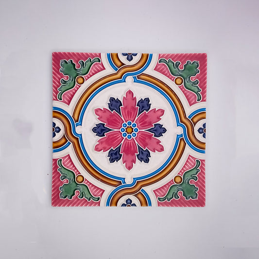 A colorful Tejo Shop Óbidos Hand Painted Wall Decor Tile featuring a symmetrical floral design with vibrant pink, blue, green, and yellow patterns on a white background.