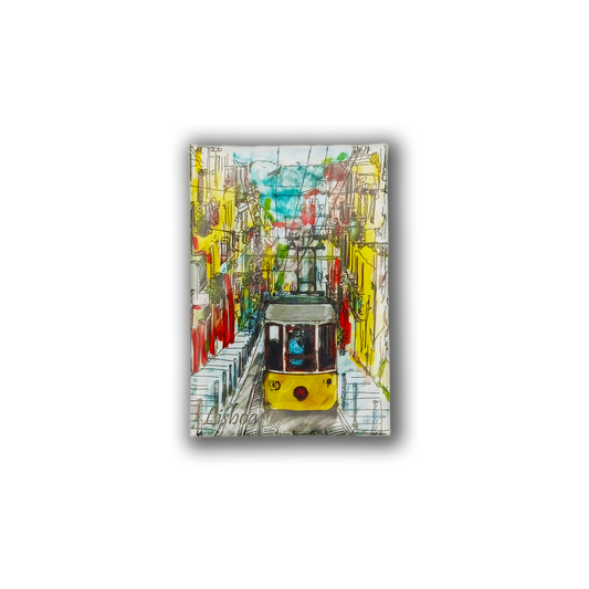 The New Jamp "Painting of a Tram - Fridge Magnet" features a colorful Lisbon tram gliding through vibrant streets with bright buildings, overhead cables, and blue sky—capturing the Portuguese spirit in a lively design.