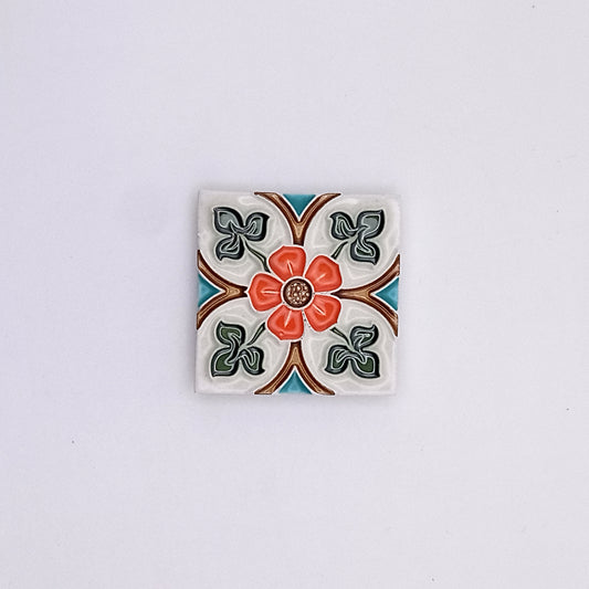 Decorative Exclusive Small Ceramic Tile from Tejo Shop with a colorful floral pattern, featuring a central red flower surrounded by green leaves and orange accents, set against a white background.