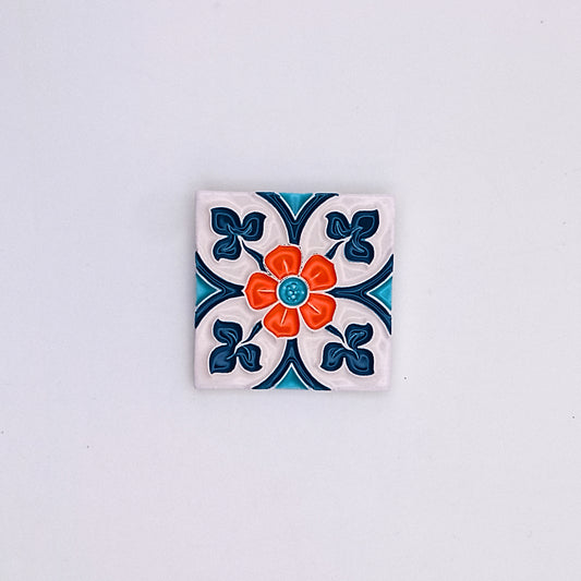 A decorative Ocean Ceramic Small Tile from Tejo Shop featuring a colorful floral design with a red center, surrounded by blue and white patterns, set against a neutral background.