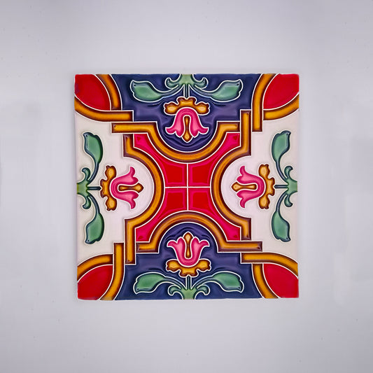 A square hand-painted Tejo Shop Mediterranean Tile with a symmetrical, colorful design featuring intricate patterns in shades of red, blue, green, and yellow on a white background.