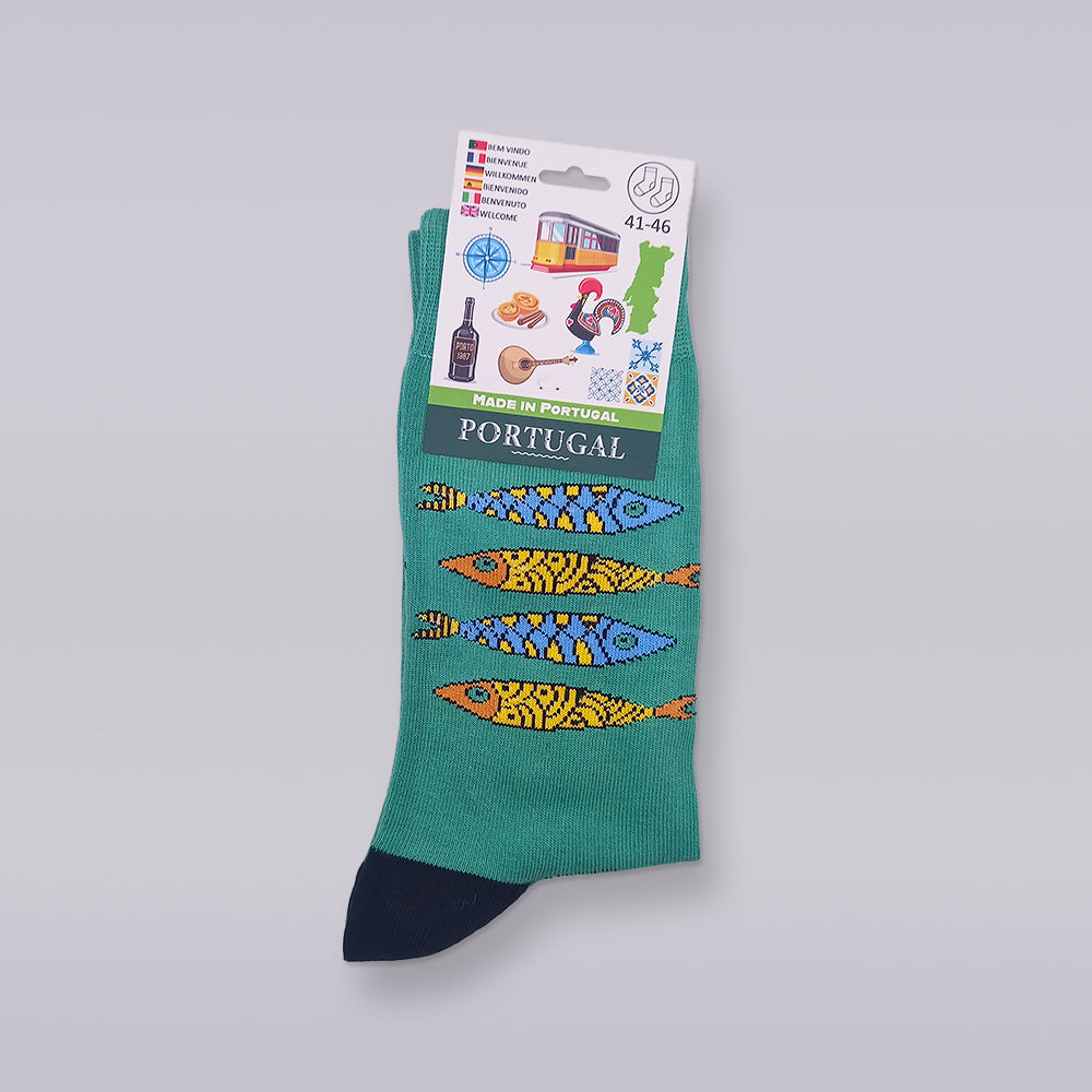 The Tejo Shop's "Socks - Portuguese Sardines Special Edition" are green, adorned with vibrant fish patterns like the iconic Portuguese sardine and "Portugal." Made of premium cotton, the packaging features images of a tram, rooster, wine, and custard tart. Available in sizes 41-46.