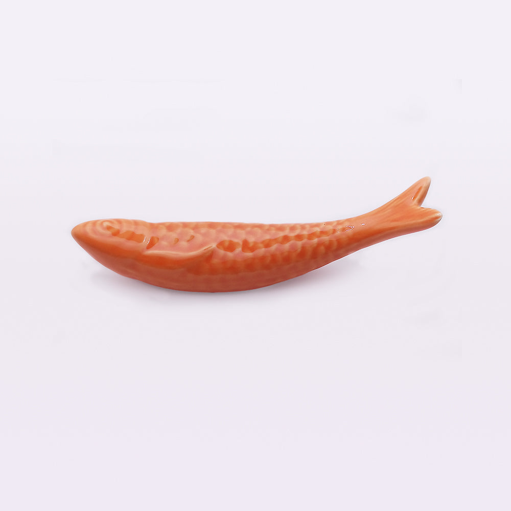 A small, orange ceramic object shaped like a fish with a textured scale pattern along its body. This handcrafted Portuguese Ceramic Sardine by Tejo Shop is displayed horizontally against a plain white background, perfect for adding a unique touch to your home decor.