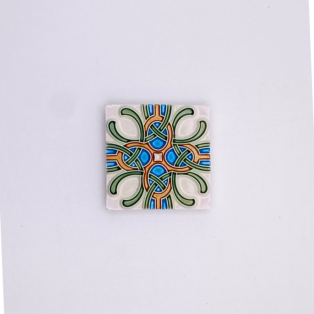 A square Small Mediterranean Tile from Tejo Shop with a symmetrical, colorful abstract design featuring interlocking shapes in blue, green, and orange on a white background.