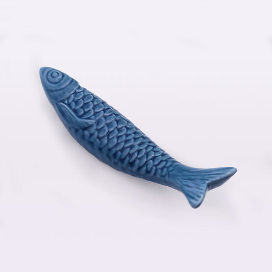 A blue ceramic fish figurine featuring detailed scales and fins, positioned on a white background. This piece of home decor appears glossy and smooth, capturing the realistic texture and shape of traditional Portuguese Ceramic Sardines by Tejo Shop.