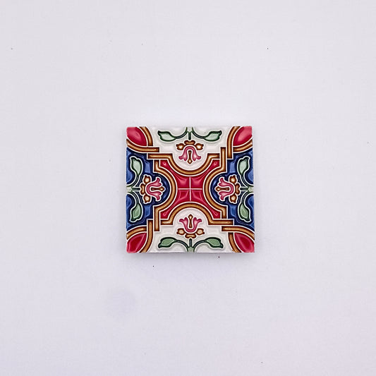 A luxury Red Velvet Small Ceramic Tile with a symmetrical floral pattern in red, green, blue, and yellow, set against a plain white background from Tejo Shop.