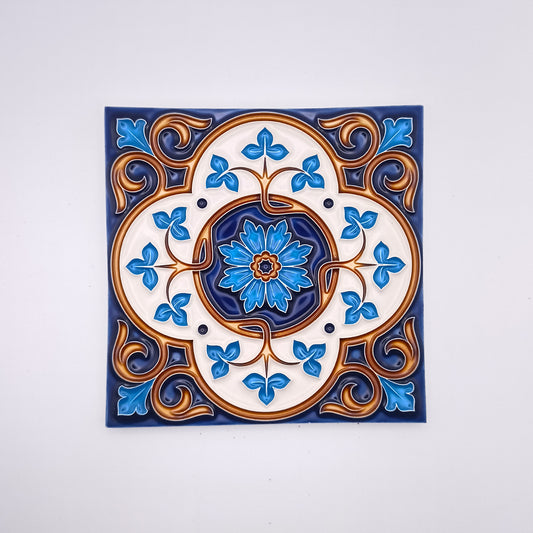 A Madeira Decor Tile from Tejo Shop featuring a symmetrical design with a central floral motif in shades of blue, surrounded by intricate gold and blue patterns, on a white background.